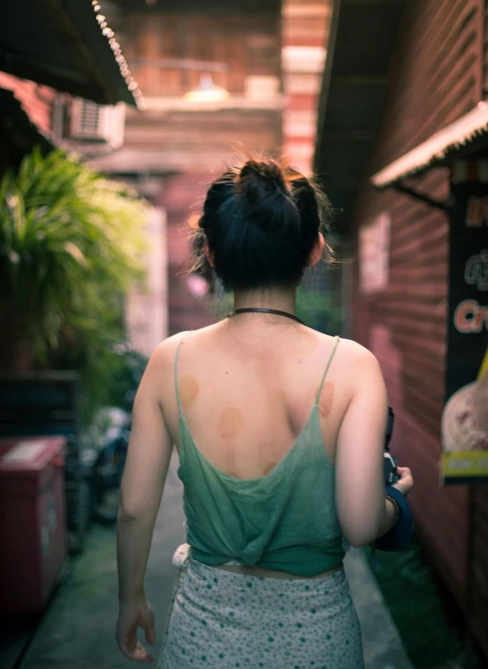 woman in a green shirt and white skirt walks down the street