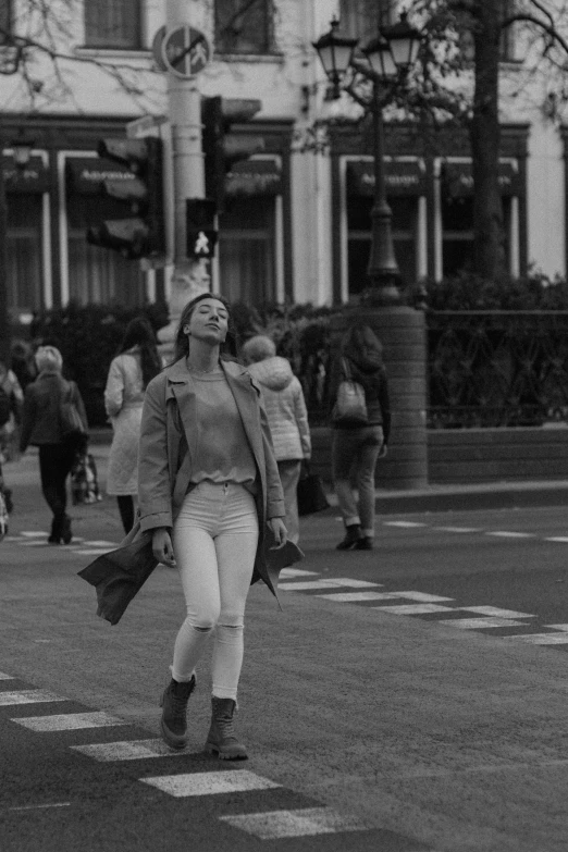 a woman is crossing the street with her hand in her pocket
