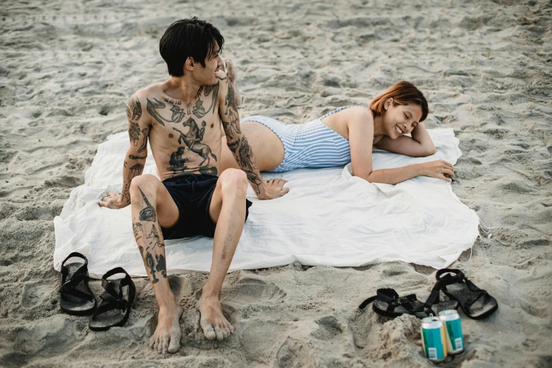 two people laying on a towel near the ocean