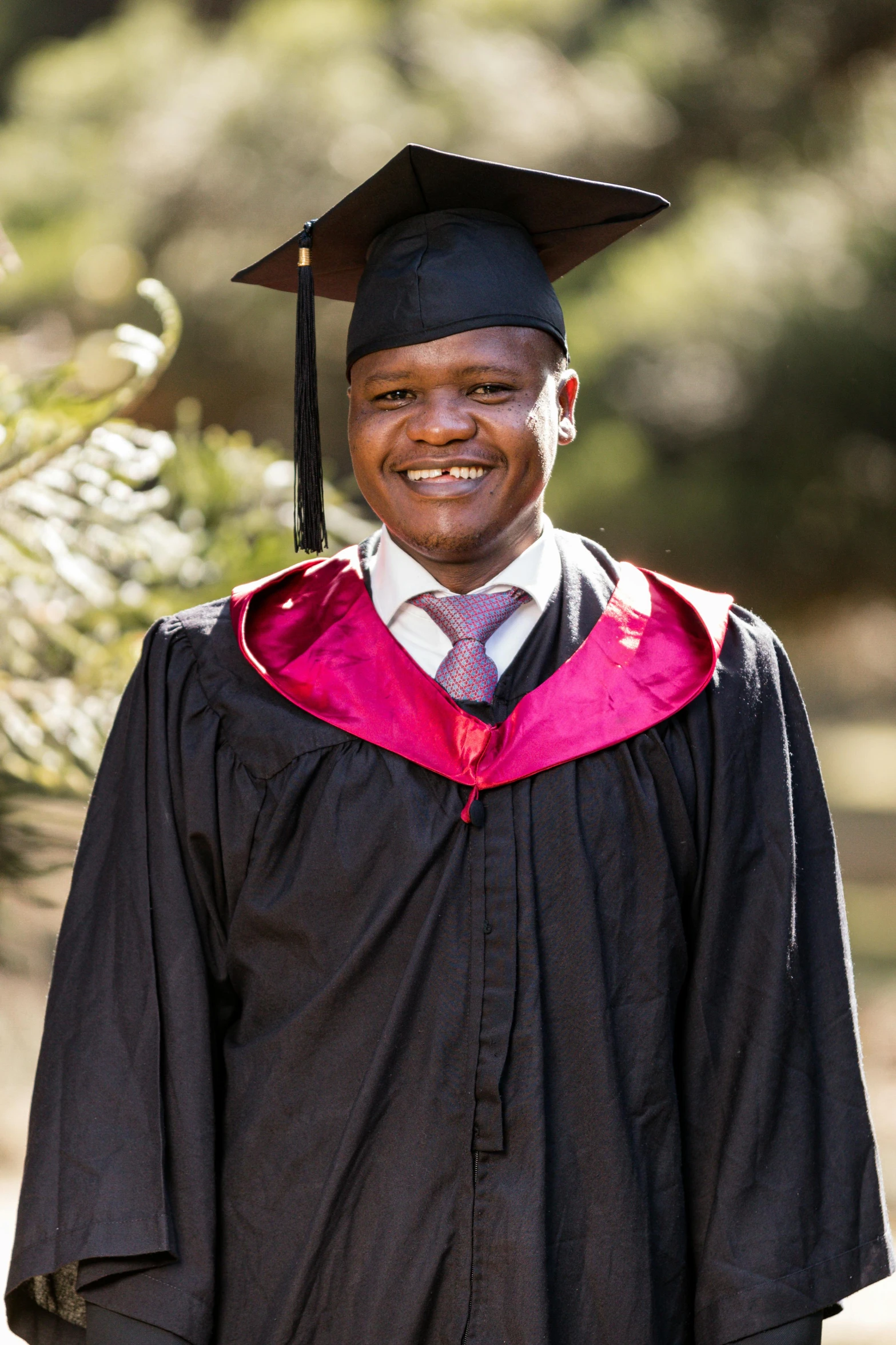 a graduate poses for a pograph outside