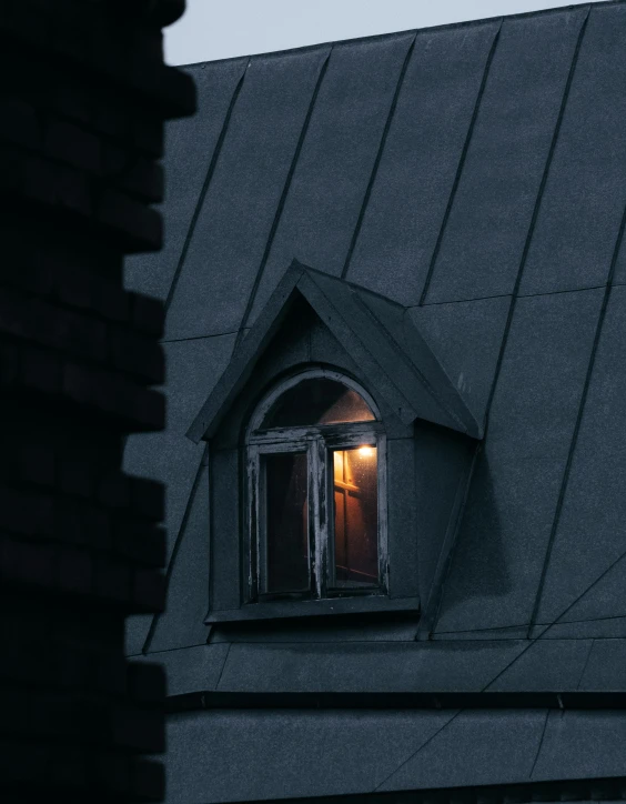 a window of a building with shingled roofs and a single candle on it