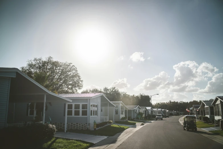 the sun shines brightly above houses near the street