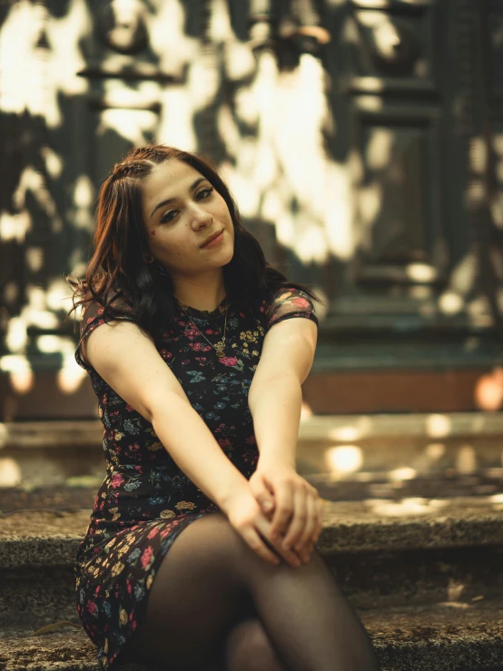 woman in dark tights sitting on stairs with sunlight coming through