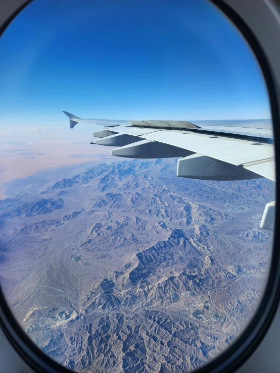 the wing of an airplane as seen through the window of another plane