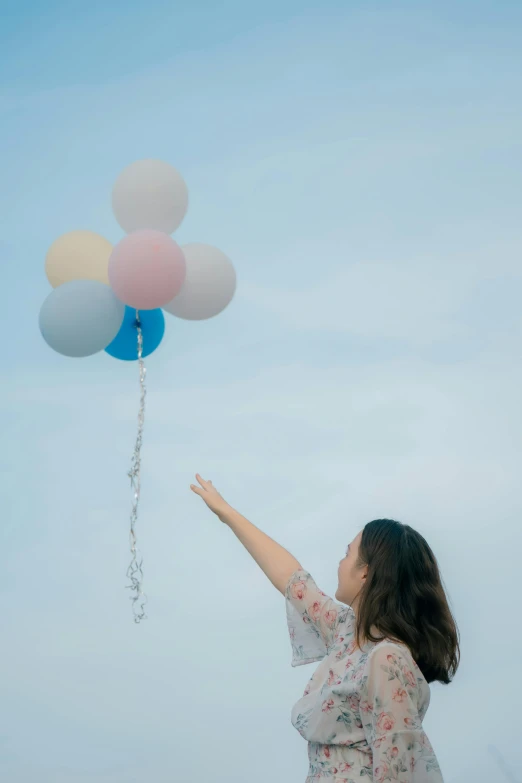 a woman flies a bunch of balloons in a cloudy sky