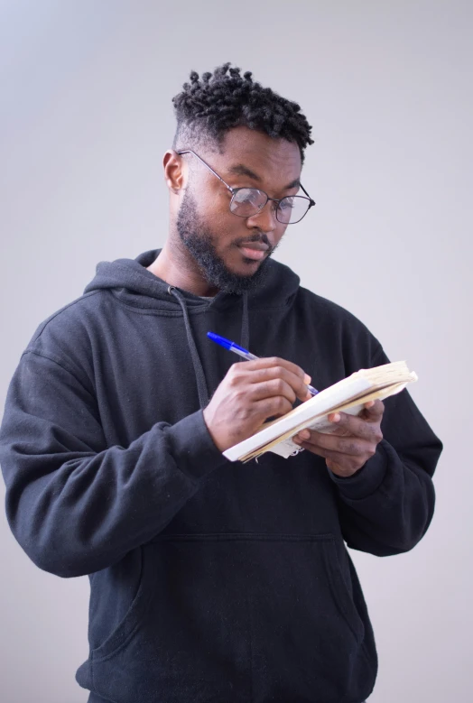 a young black man with glasses looks down at a piece of paper