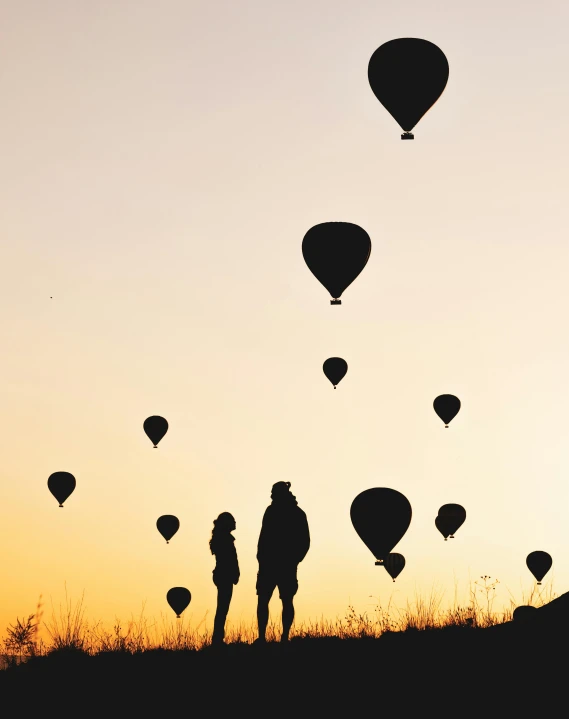 a group of balloons floating up into the sky with a couple