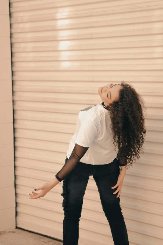 a woman wearing jeans standing next to a building