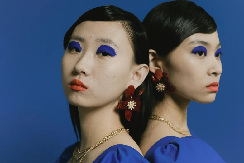 a pair of women with bright blue eyeliners and a flower in their hair
