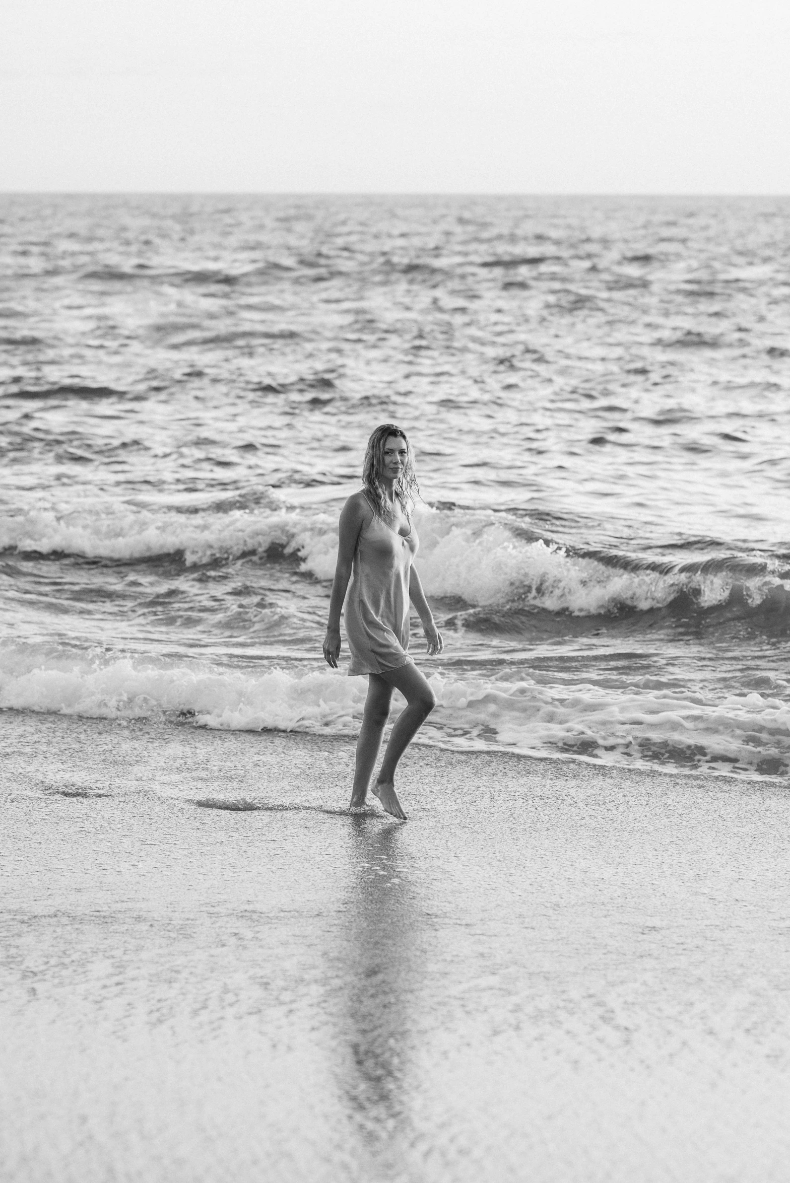 a woman standing on the beach watching an ocean