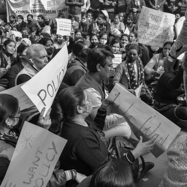 many people holding signs on the ground while sitting