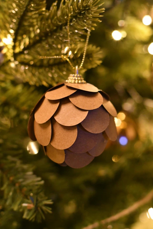 an ornament shaped like a pine cone hanging from the nches of a christmas tree