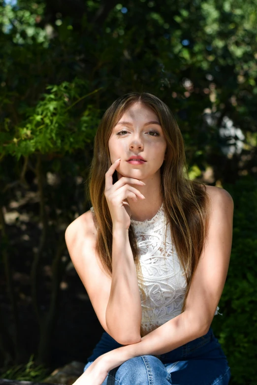 a young woman sitting on top of a bench with her chin resting on her hand