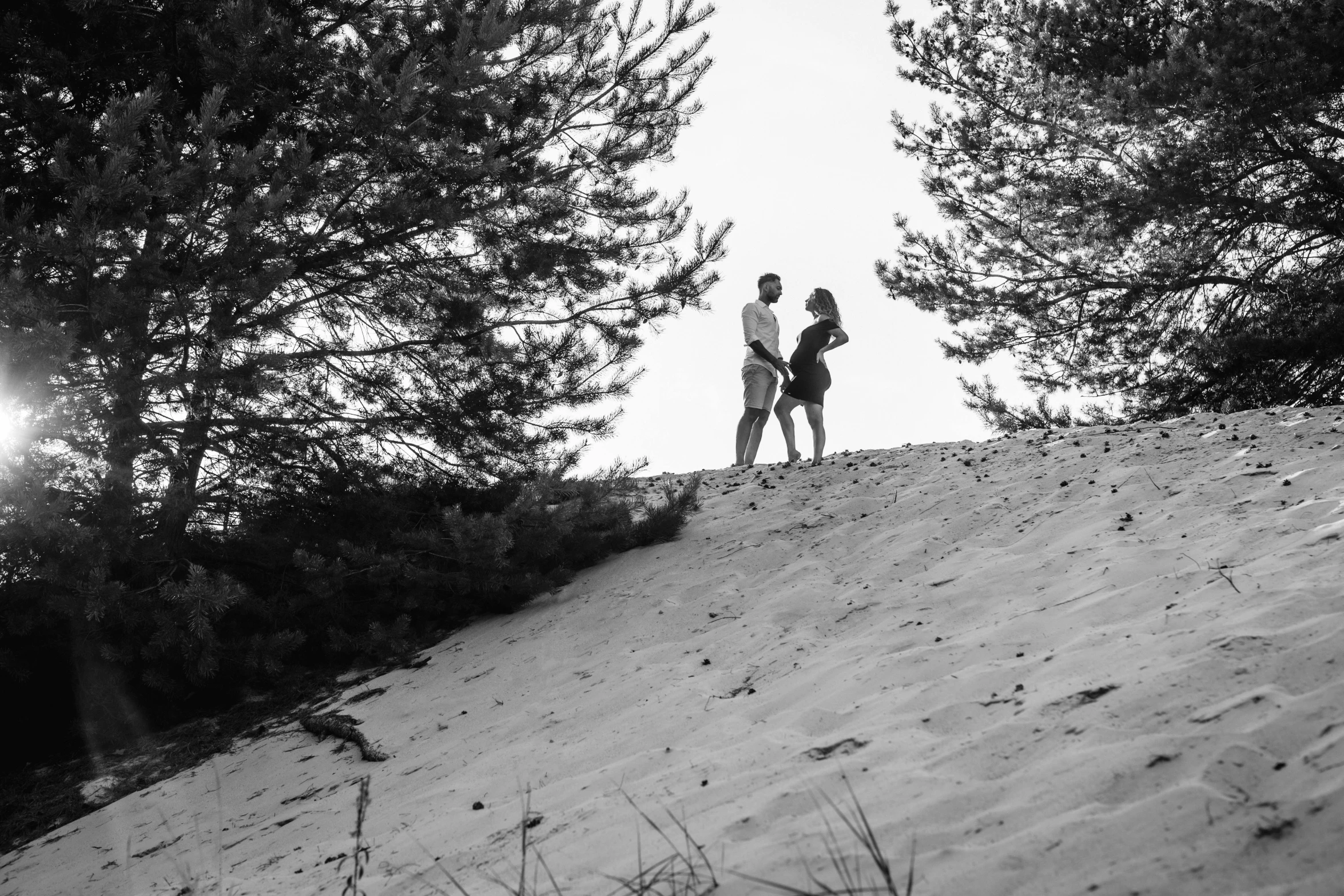 two people standing on a steep hill in black and white