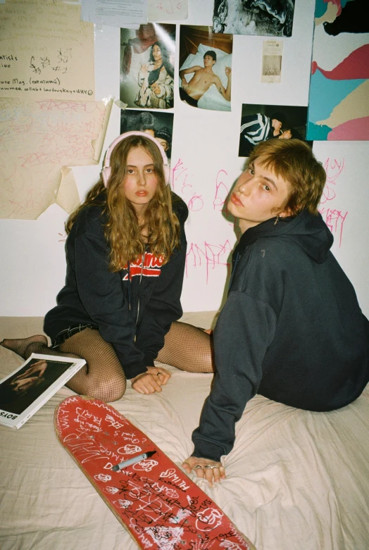 two young women sitting on a bed with a snowboard