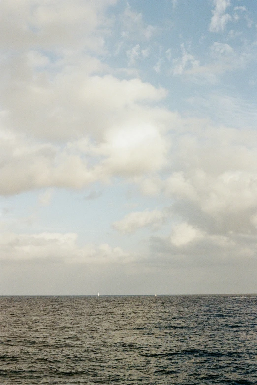 a very pretty blue ocean with some white clouds in it