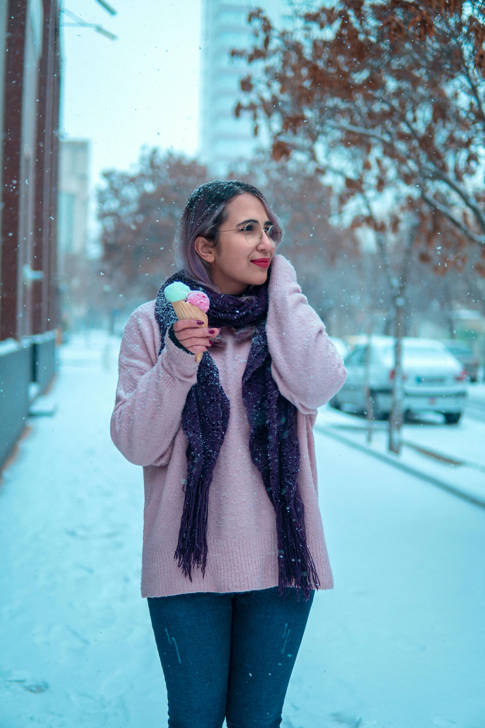 a woman wearing a pink sweater and scarf holding a snowball