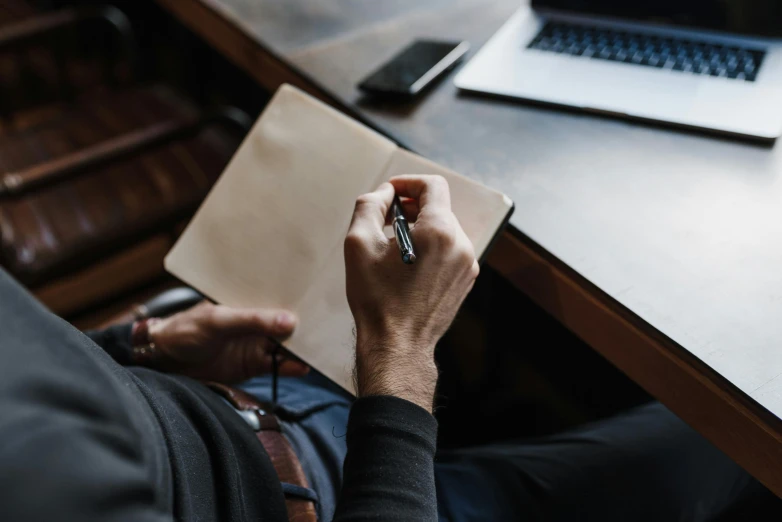 a man with a pen in his hand is on a notebook