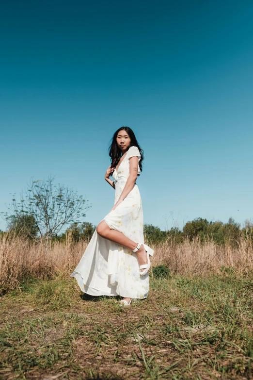 a woman is standing in the grass while wearing white