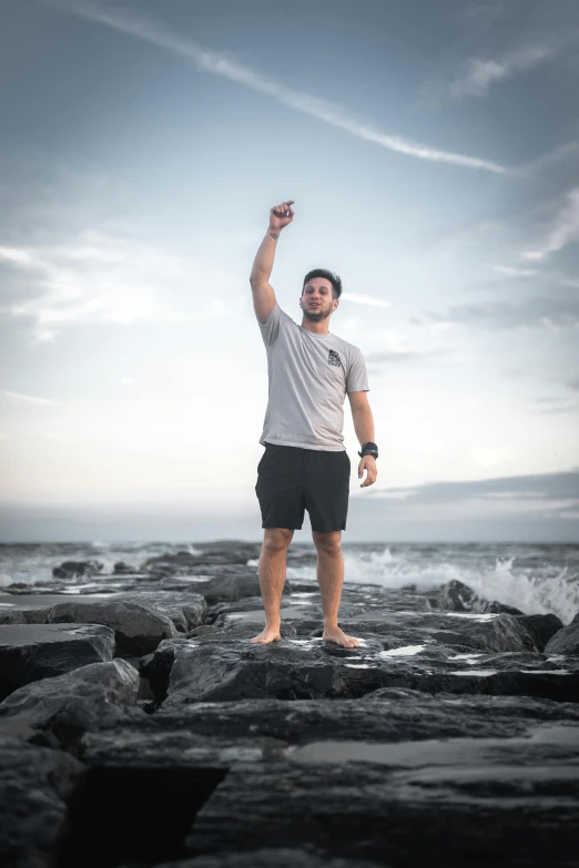 a man is standing on some rocks near the water