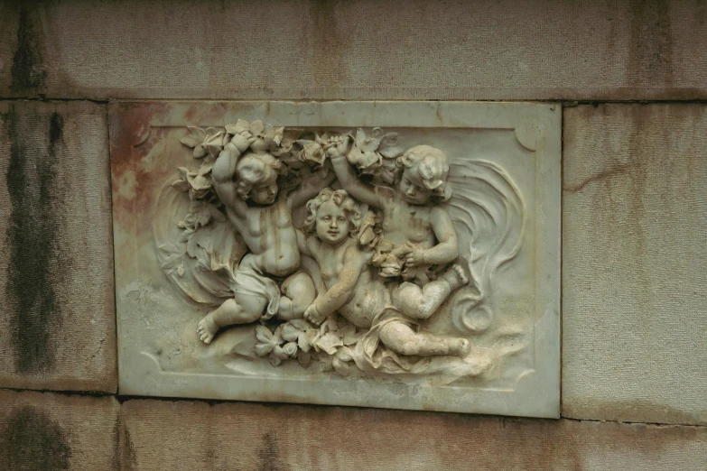 a stone wall decoration featuring an angel holding a snake