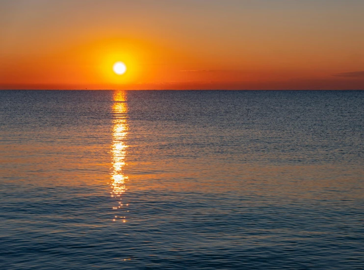 the sun setting over the ocean on a clear day