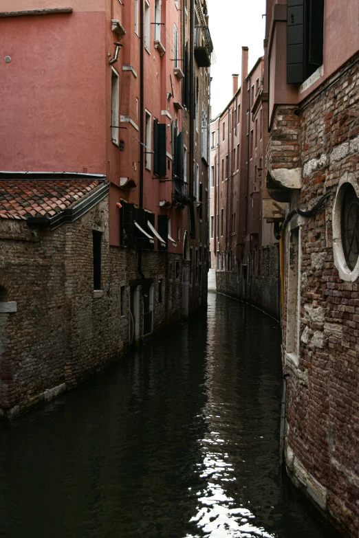 the narrow waterway runs along the side of red brick buildings