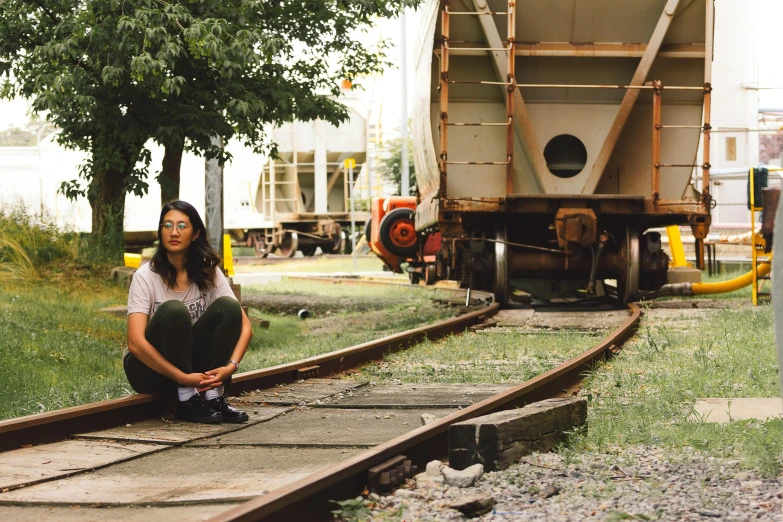 a woman crouches on tracks to admire the back of a large truck