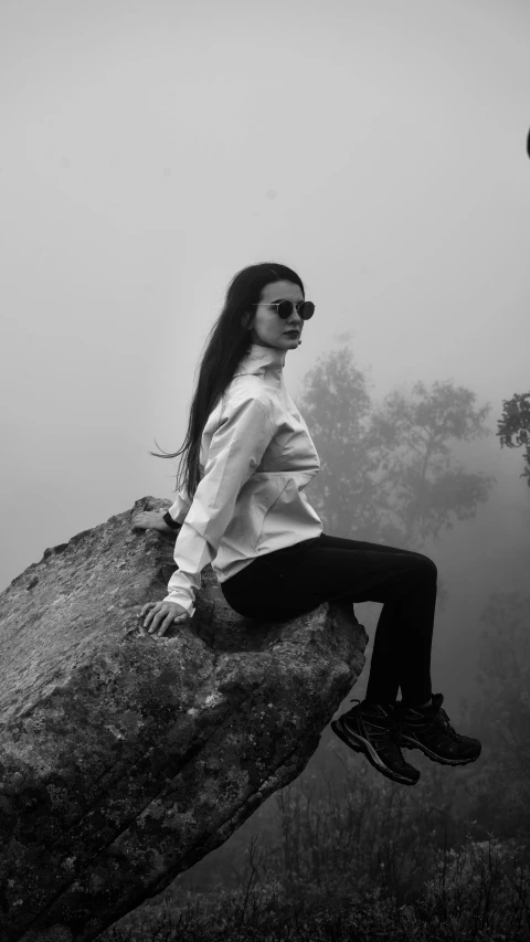 a woman with long hair sitting on a rock