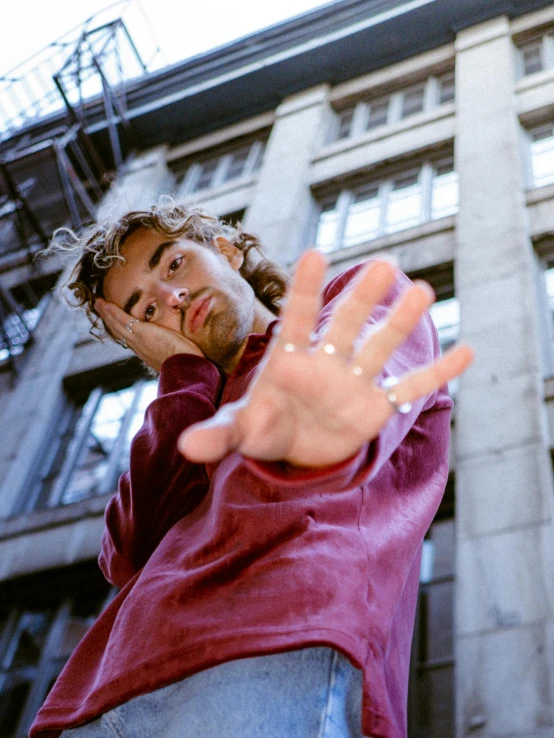 a man standing in front of a tall building holding his hand up