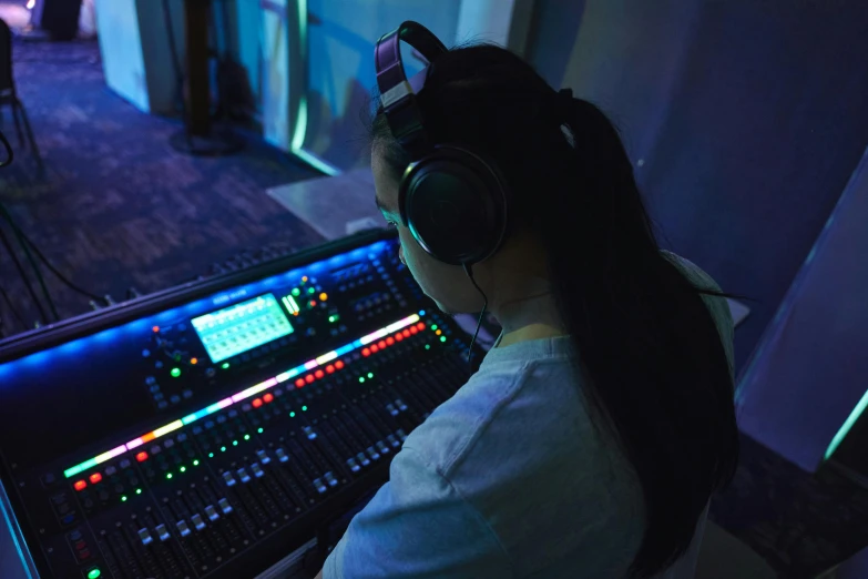 a woman wearing headphones next to an audio mixing console