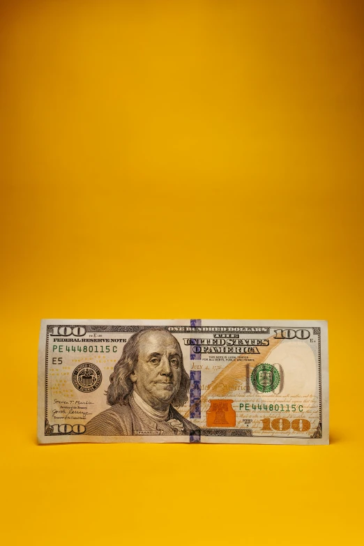 a five dollar bill against a yellow backdrop