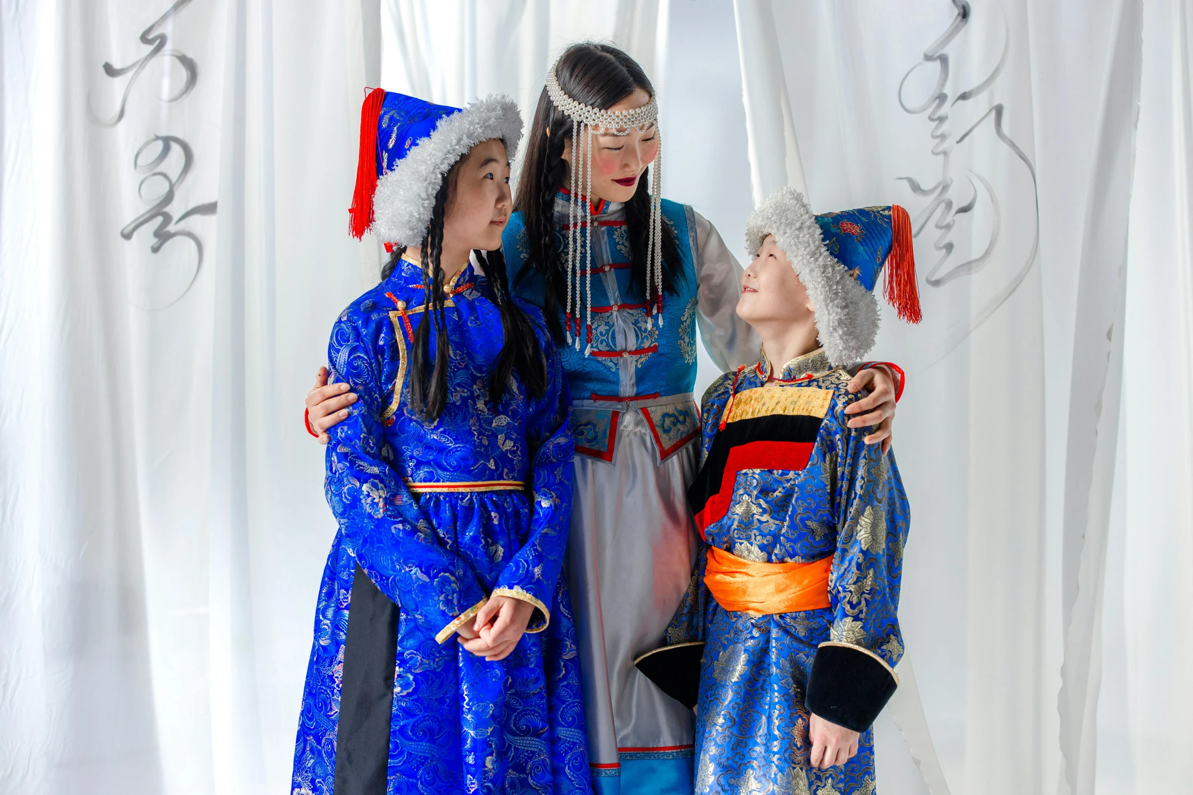 three children stand next to each other near curtain