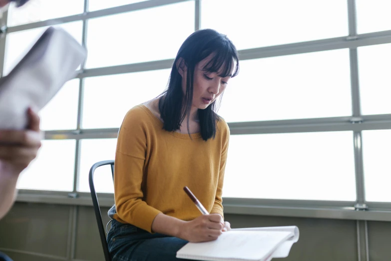 a woman writing while sitting in a chair