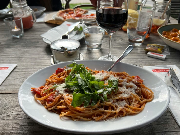 a plate of pasta, garnished with parmesan and fresh herbs