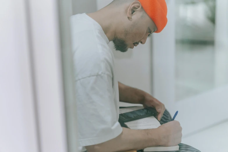 there is a man wearing a red turban, writing on his notebook