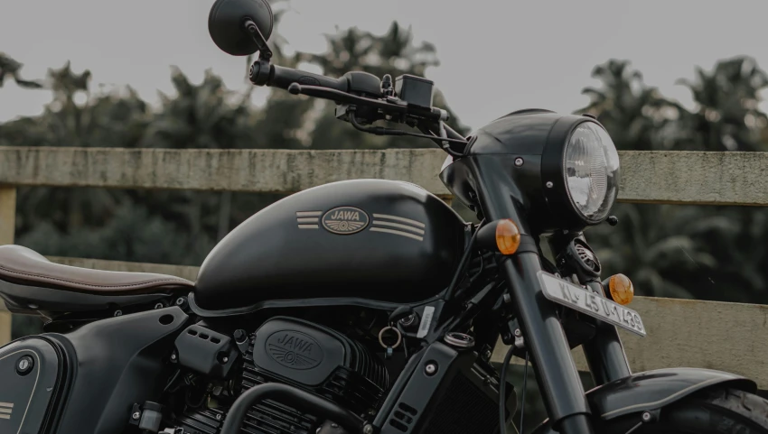 motorcycle parked next to a wooden fence with trees in background