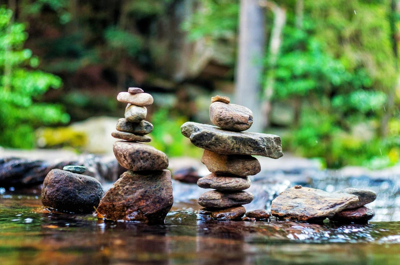 several rocks stacked in the water near some trees