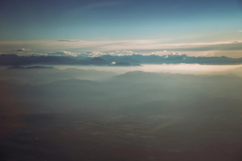 a large wing flies above a mountain range