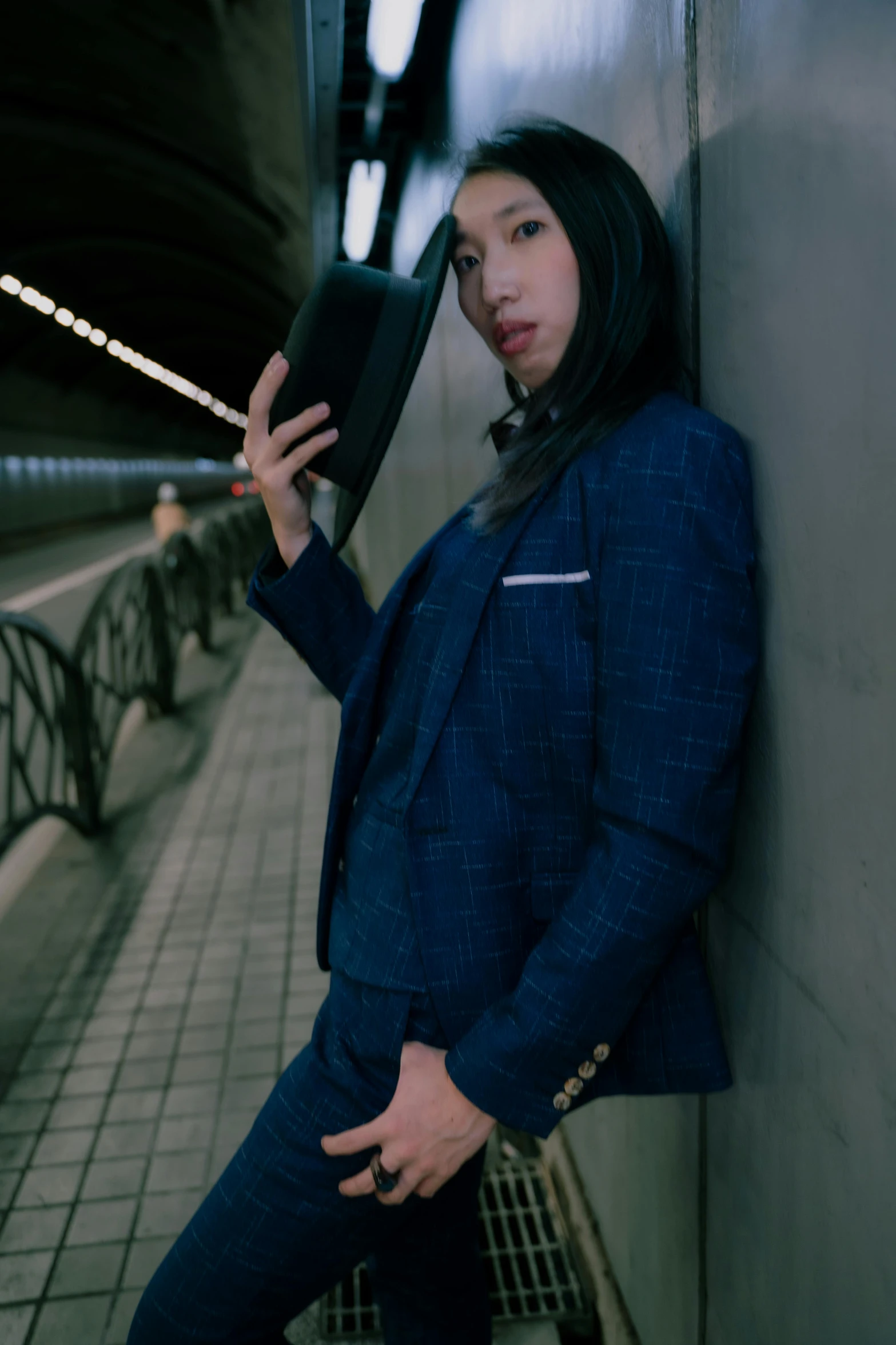 a woman leaning on the wall in front of a subway