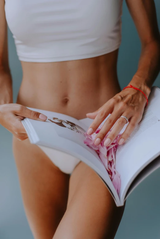 the woman is showing off her slim body while reading a book