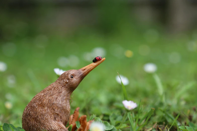 a close up of a toy bird sitting on grass