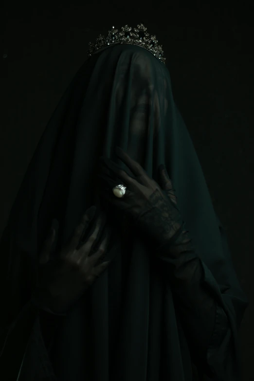 a woman in a veil covering her head with hands and a ring on her finger