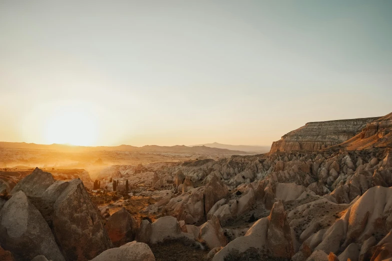 the sun setting over mountains with rock formations