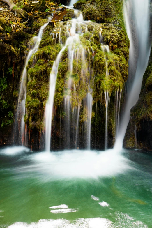 a view of the water coming out of the waterfall, with green vegetation