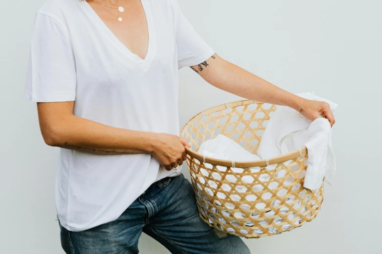 a woman is holding a basket full of clothes