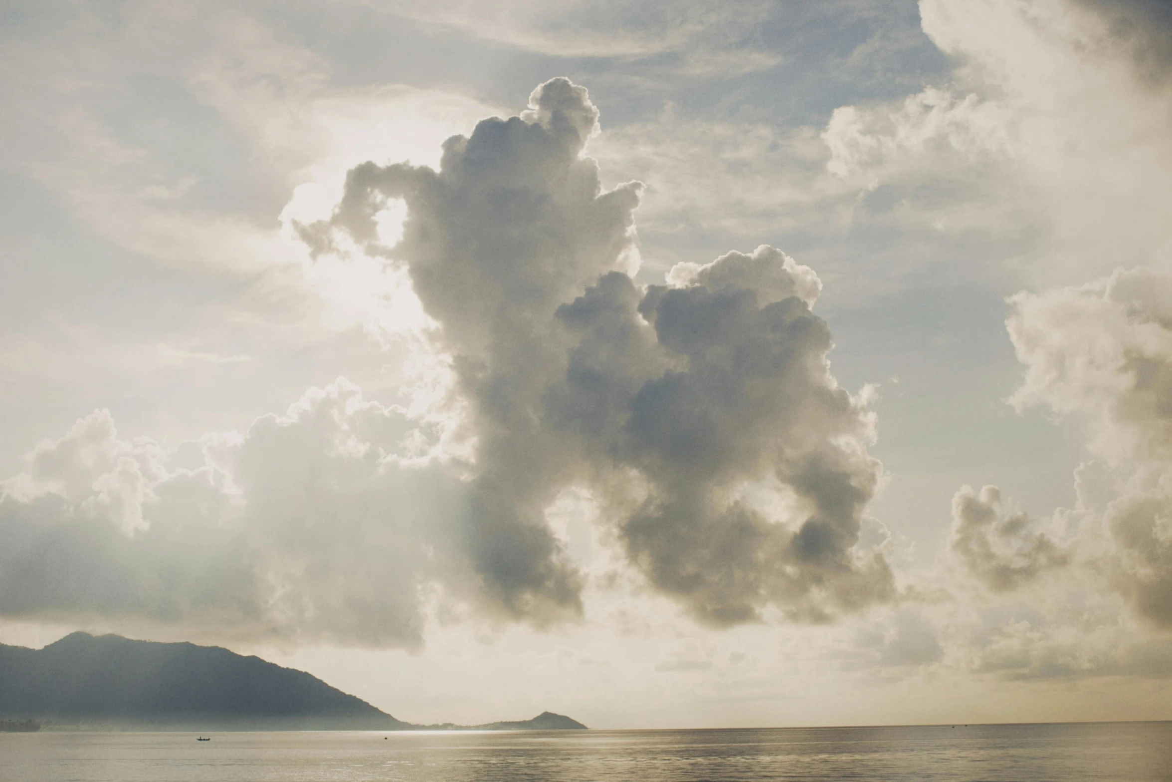 many clouds and mountains with the ocean below