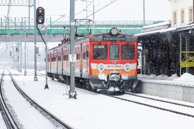 the red train has stopped at the snow covered station