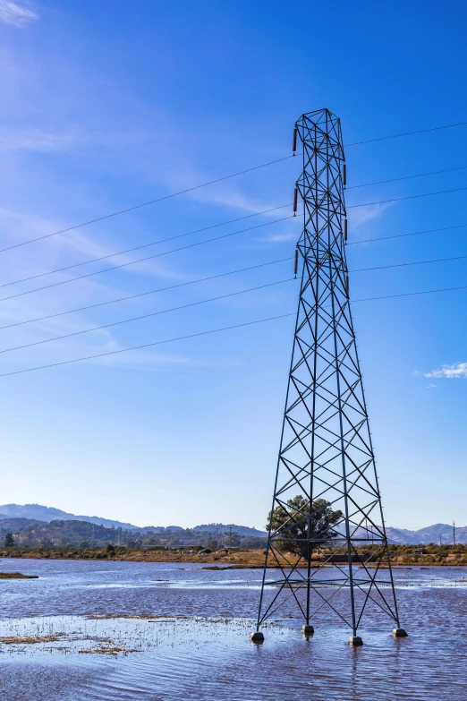 water covering a lake near a large tower with wires