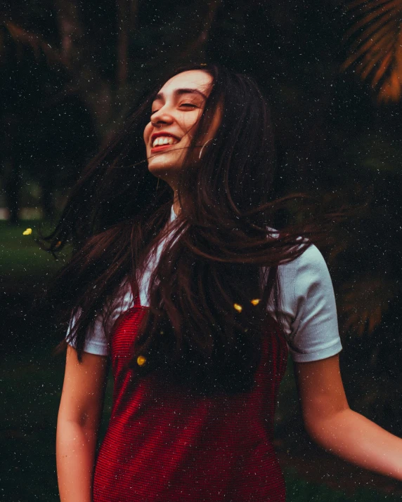 a woman with long hair and red overalls smiling